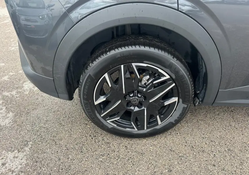 Gros plan sur la roue avant gauche du Peugeot 3008 Hybrid gris 2025 avec jante alliage noire et argent 19 pouces.