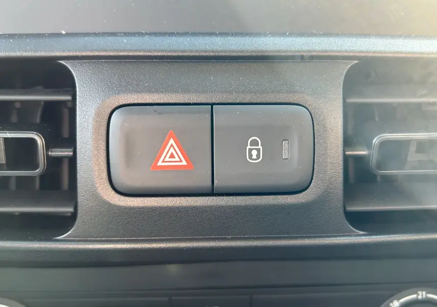 Gros plan sur les boutons d’alerte et de verrouillage central du tableau de bord du DANGEL Partner gris Artense.