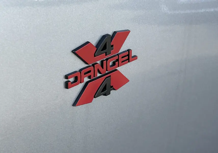 Gros plan sur le logo 4x4 Dangel rouge et noir apposé sur la carrosserie gris artense du Peugeot Partner.