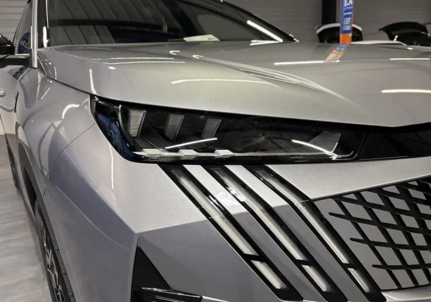 Gros plan sur l'avant gauche du Peugeot 3008 gris Artense, mettant en valeur les phares LED et la calandre distinctive.