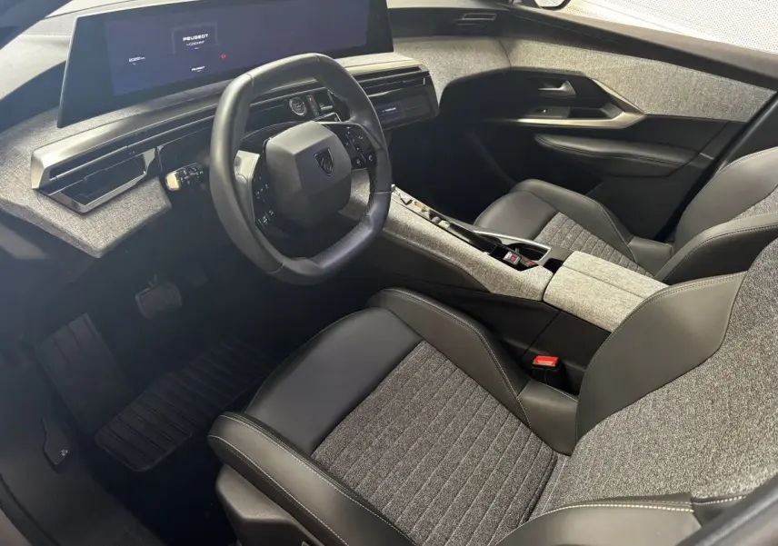 Vue intérieure côté conducteur du Peugeot 3008 2025 hybride, avec sièges bi-matière gris et noir et tableau de bord digital.