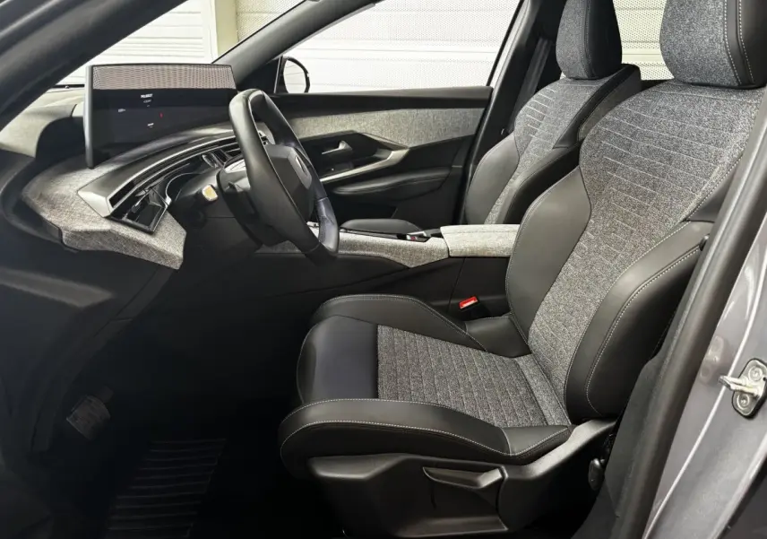 Vue intérieure côté conducteur du Peugeot 3008 gris clair 2025, sièges tissu et cuir, tableau de bord moderne avec écran tactile.