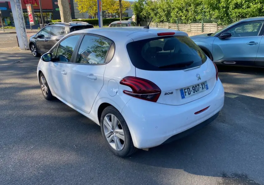 Peugeot 208 blanche vue en 3/4 arrière droit, avec feux arrière distinctifs et plaque d'immatriculation française.