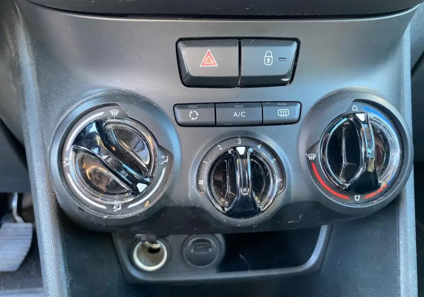 Gros plan sur les commandes de climatisation et boutons de sécurité du tableau de bord de la Peugeot 208 blanche 2019.
