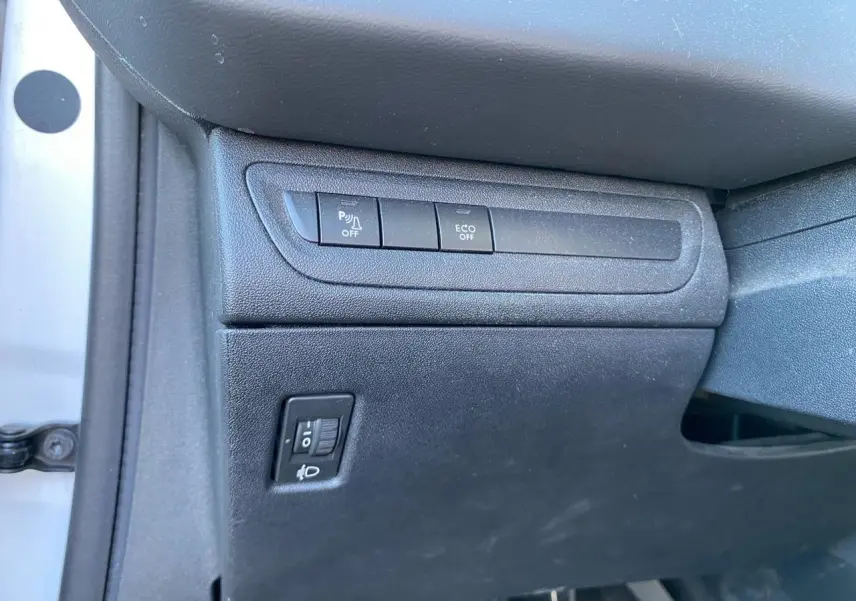 Détail intérieur côté conducteur du Peugeot 208 blanc 2019 montrant les commandes d’aide au stationnement et mode ECO.