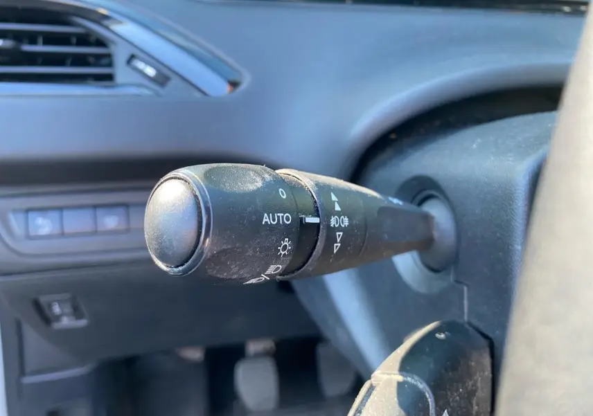 Gros plan sur la commande des feux à gauche du volant dans l’habitacle d’une Peugeot 208 blanche de 2019.