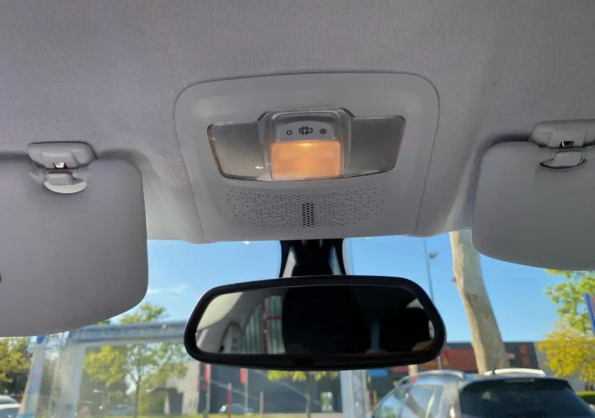 Vue intérieure centrée sur le plafonnier et le rétroviseur intérieur d’une Peugeot 208 blanche, avec pare-soleil baissé.