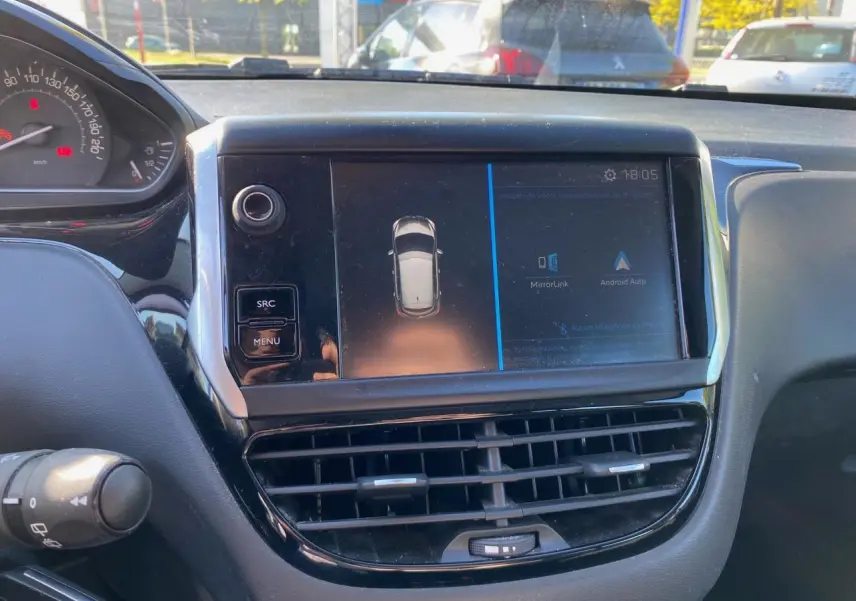 Vue rapprochée du tableau de bord de la Peugeot 208 blanche de 2019, avec écran tactile et commandes visibles.