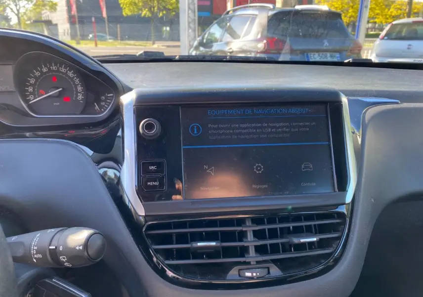 Vue intérieure du tableau de bord de la Peugeot 208 blanche de 2019, avec écran tactile et combiné de vitesse visible.