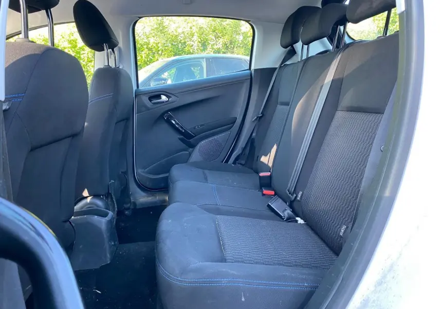 Vue intérieure arrière côté droit des sièges noirs avec surpiqûres bleues d'une Peugeot 208 blanche de 2019.