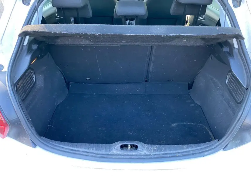 Coffre ouvert vu de l'arrière d'une Peugeot 208 blanche, montrant l'espace de chargement et la banquette arrière.