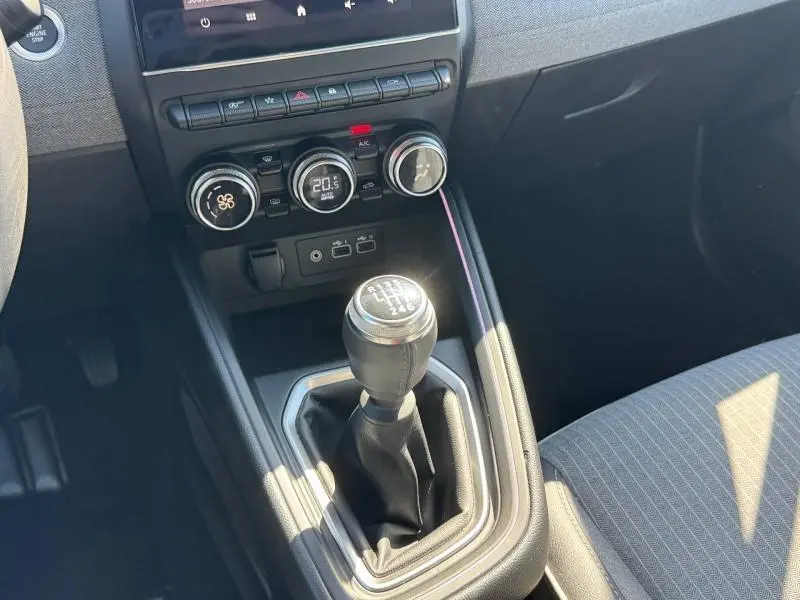Vue rapprochée de la console centrale de la Renault Clio 1.0 Eco-G 2025 avec levier de vitesses manuel et commandes de climatisation.