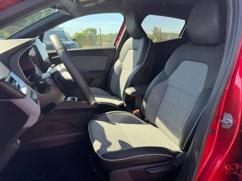 Vue intérieure côté conducteur de la Renault Clio 1.0 Eco-G 100ch Techno 2025 rouge, sièges tissu gris et noir.