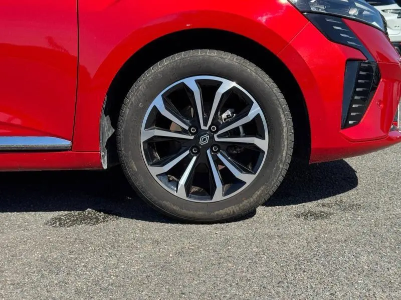 Gros plan sur la roue avant gauche d'une Renault Clio rouge 2025, mettant en valeur la jante alliage au design moderne.