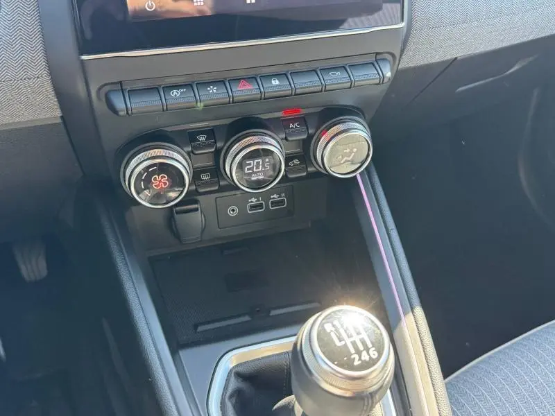 Vue intérieure centrée sur la console centrale de la Renault Clio 2025, avec commandes climatisation et levier de vitesse manuelle.