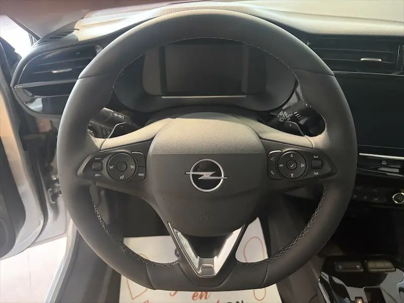 Vue rapprochée du volant noir de l'Opel Corsa 1.2 Turbo 100 Edition 2025 avec commandes intégrées, intérieur gris visible.