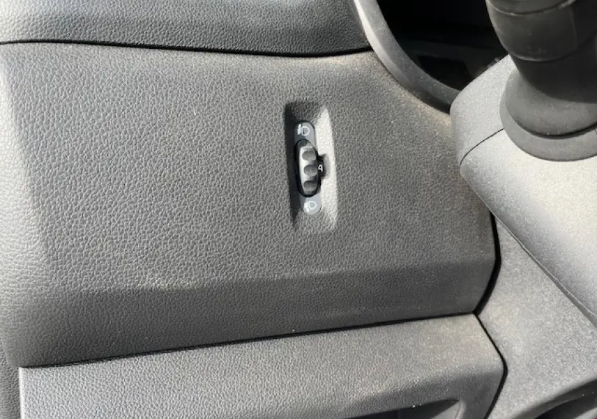 Gros plan sur le réglage des phares dans l’habitacle noir du Renault Master 2.3 dCi 130 Benne Basculante 2024.