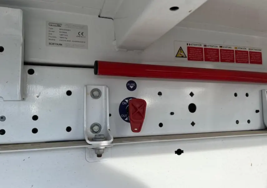 Détail du mécanisme de la benne basculante blanche Renault Master 2.3 dCi 130, vue rapprochée du levier rouge et cadre métallique.