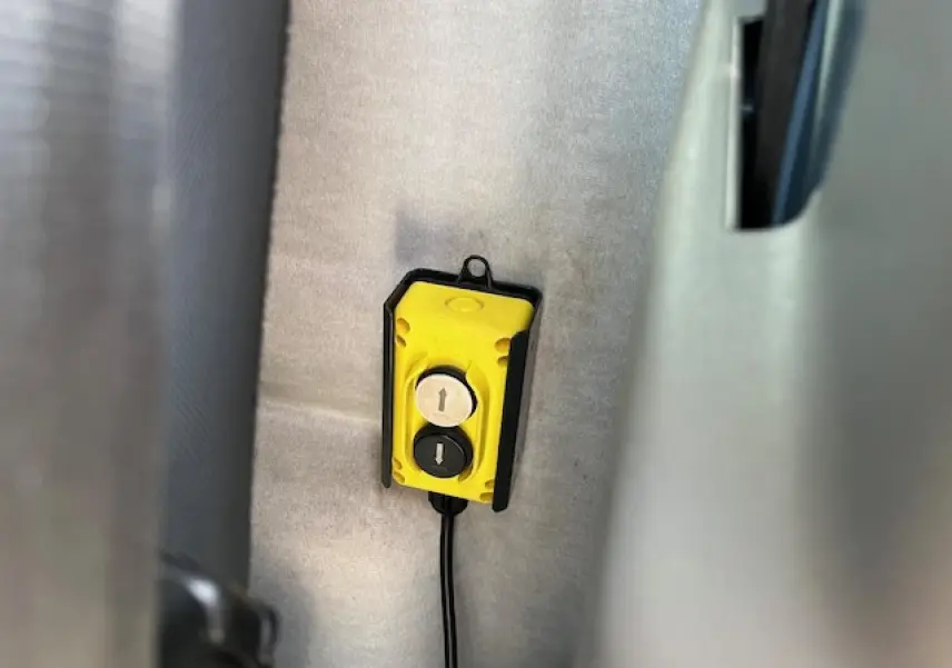Vue intérieure rapprochée d’un bouton de commande jaune pour la benne basculante du Renault Master blanc 2024.