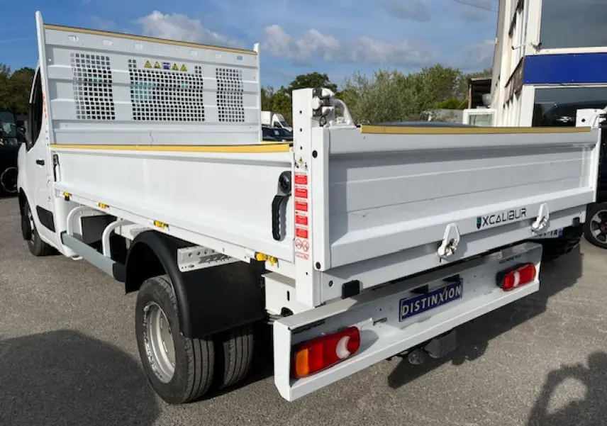 Vue 3/4 arrière droite du Renault Master blanc 2024 avec benne basculante et double roues arrière.