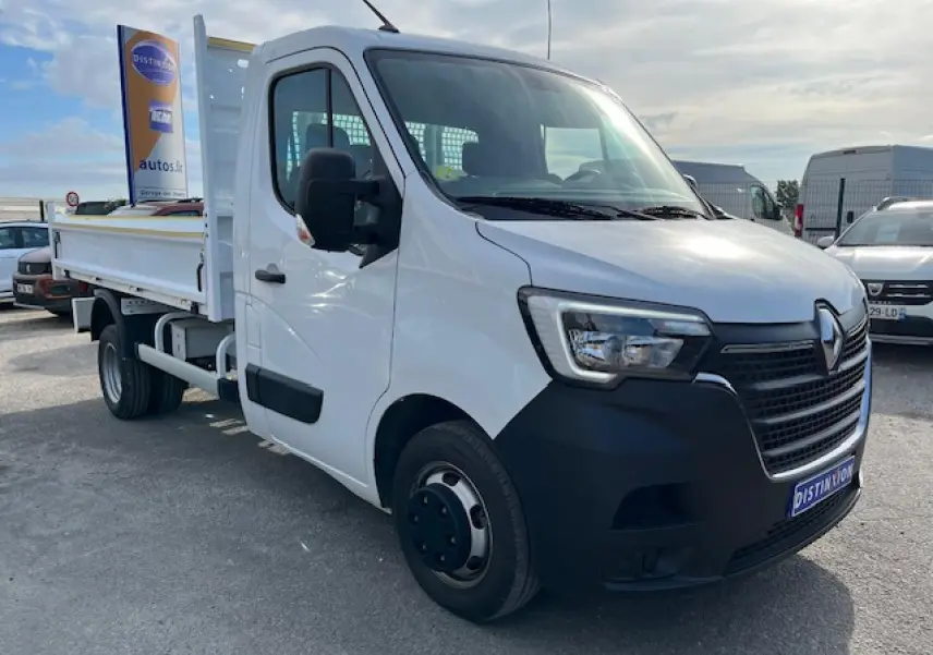 Renault Master blanc en 3/4 avant droit, benne basculante visible, calandre noire et pare-chocs avant noir.