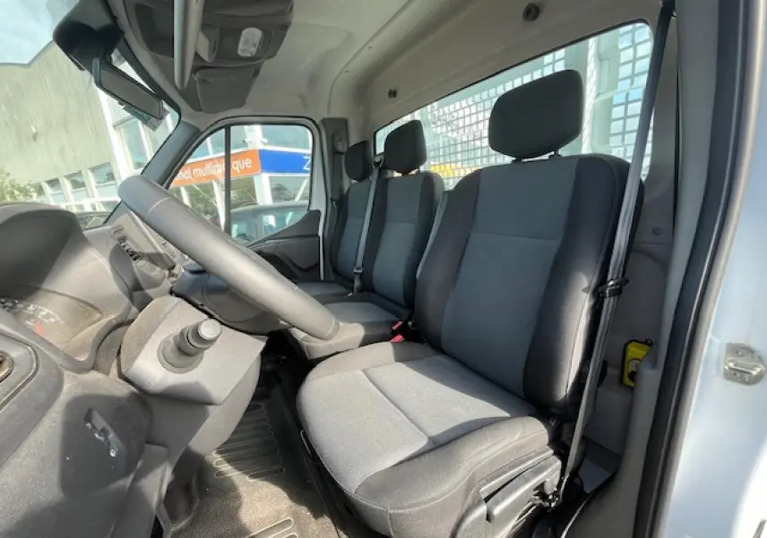 Intérieur du Renault Master 2024 vu côté conducteur, montrant les sièges gris et le volant à gauche.
