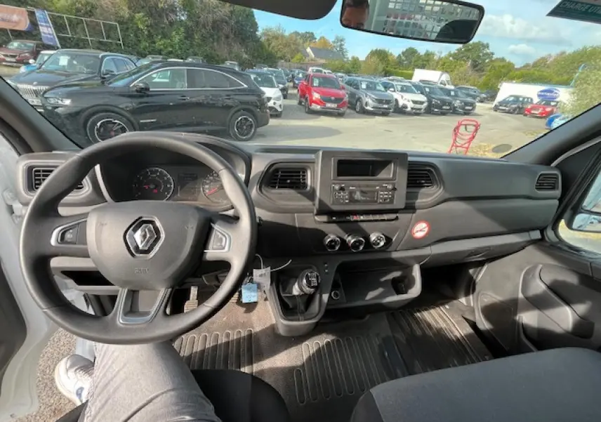 Vue intérieure du poste de conduite du Renault Master blanc 2024, avec volant, tableau de bord et levier de vitesses manuel visibles.