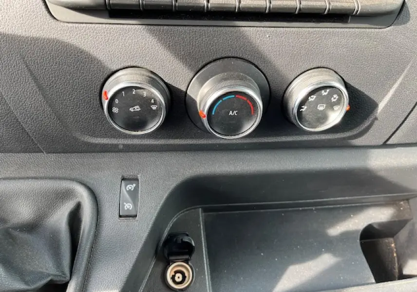 Détail du tableau de bord du Renault Master 2024 blanc, montrant les commandes de climatisation et la prise 12V.
