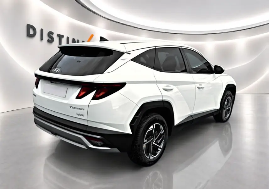 Vue 3/4 arrière droite d'un Hyundai Tucson blanc hybride avec jantes alliage et vitres teintées en showroom.