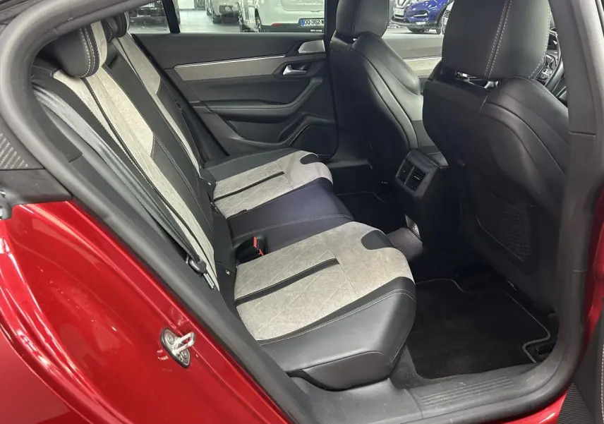 Vue côté gauche de l'habitacle arrière rouge clair d'une Peugeot 508 Hybrid avec sellerie bicolore cuir et alcantara.