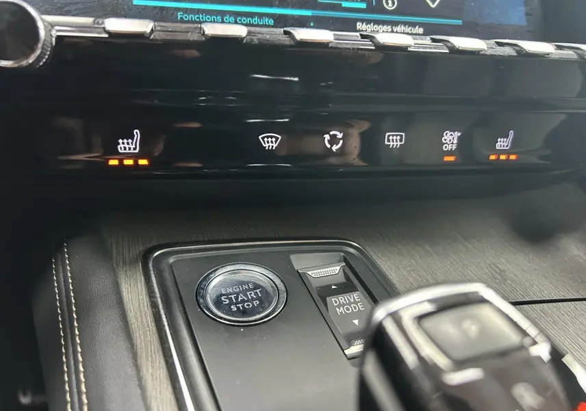 Gros plan sur la console centrale du Peugeot 508 Hybrid rouge clair, avec bouton start/stop et commandes chauffage activées.