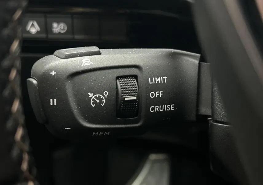 Gros plan sur la commande de régulateur de vitesse du Peugeot 508 Hybrid rouge clair, avec molette et pictogrammes blancs.