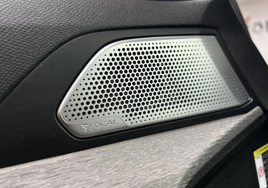 Gros plan sur l'enceinte Focal intégrée à la porte intérieure noire d'une Peugeot 508 Hybrid rouge clair.