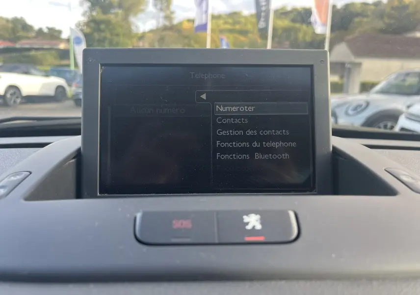 Écran GPS central affichant le menu téléphone dans l'habitacle du Peugeot 5008 2013, avec bouton SOS et logo Peugeot visible.
