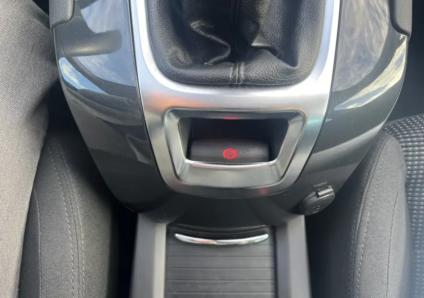 Gros plan sur la console centrale noire du Peugeot 5008 2013, mettant en valeur le frein à main électrique rouge et le levier de vitesse.