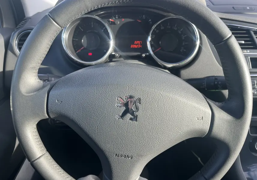 Vue rapprochée du volant en cuir noir avec logo Peugeot du 5008 1.6 HDI 114 Allure diesel de 2013.