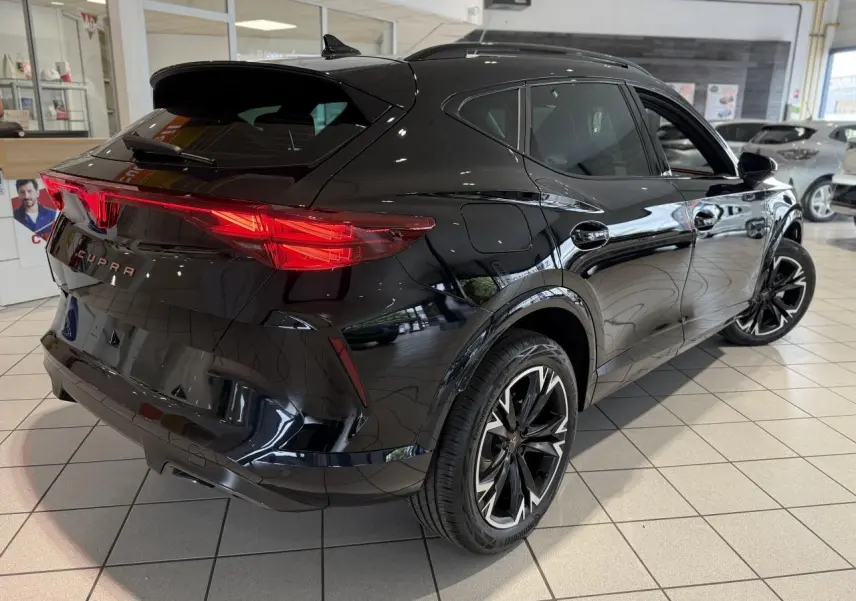Vue 3/4 arrière droite du CUPRA Formentor noir Night avec feux arrière LED et jantes alliage 18 pouces en showroom.