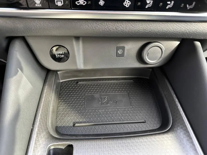 Vue rapprochée de la console centrale du Nissan Qashqai Hybrid e-POWER 2025, avec zone de recharge sans fil et bouton start/stop.