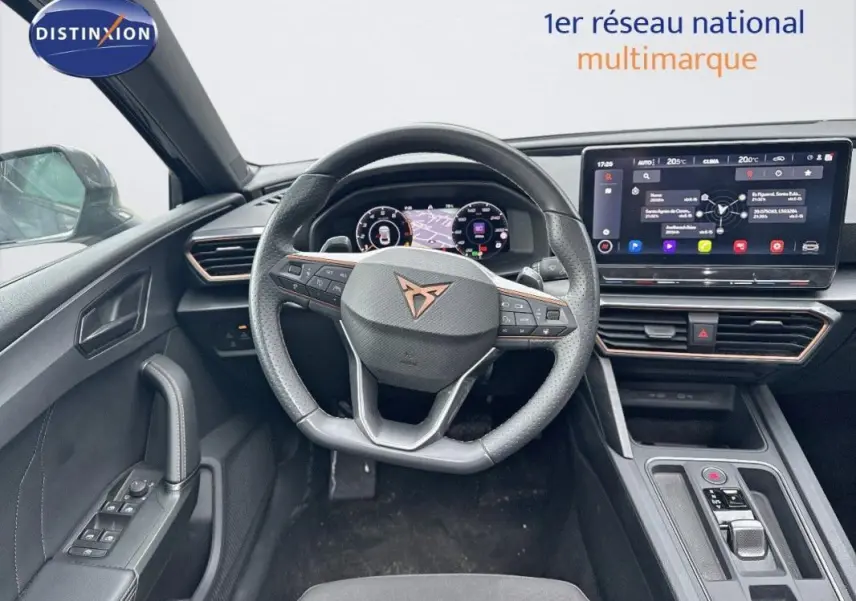 Vue intérieure centrée sur le volant cuir et le cockpit numérique du CUPRA Leon ST 2024, avec écran tactile et commandes au volant.