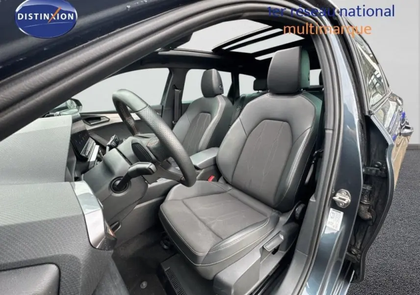 Vue intérieure côté conducteur de la CUPRA Leon ST gris 2024 avec toit ouvrant panoramique et sièges cuir noirs.