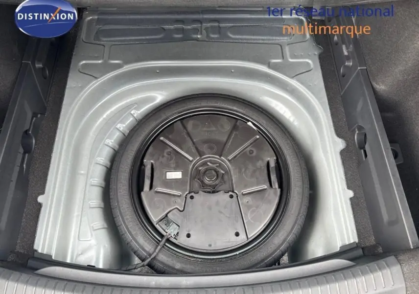 Vue plongeante sur la roue de secours dans le coffre d'une CUPRA Leon ST gris 2024, espace de rangement visible.
