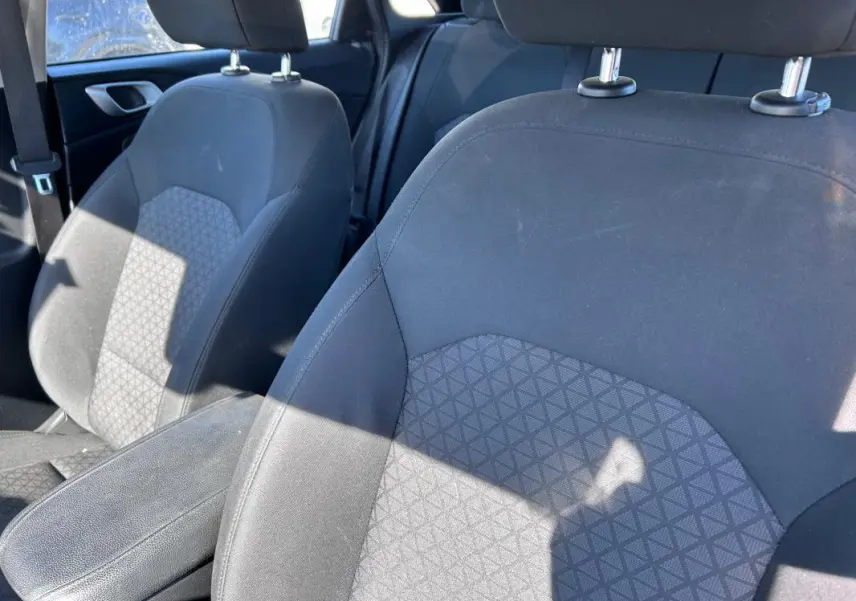 Gros plan sur les sièges avant gris de la KIA CEE'D 2022 avec accoudoir central et tissu à motifs géométriques.