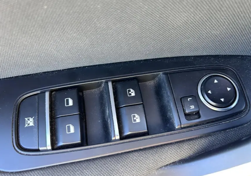 Gros plan sur les commandes des vitres électriques et rétroviseurs réglables côté conducteur d’une KIA CEE'D gris 2022.