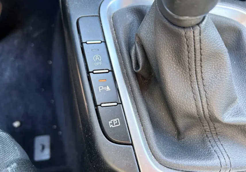 Gros plan sur la console centrale grise de la KIA CEE'D 2022 avec levier de vitesse manuel et boutons de contrôle.