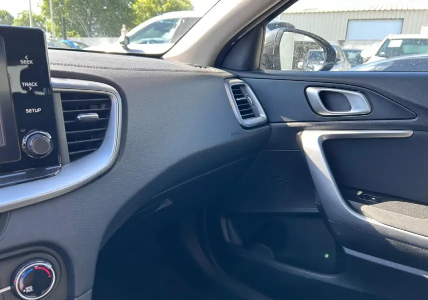Intérieur côté passager de la Kia CEE'D gris 2022, montrant tableau de bord, aérateurs et porte avec poignée argentée.