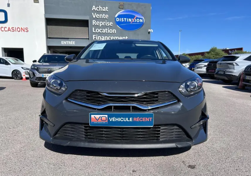 Vue frontale d'une KIA CEE'D gris 2022 avec calandre noire et plaque "Véhicule récent" en concession.