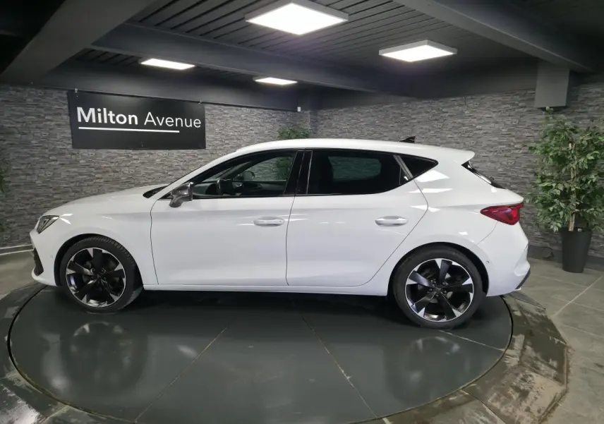 Vue latérale droite d'une CUPRA Leon blanche Nevada 2023 avec jantes alliage 18 pouces et vitres teintées.