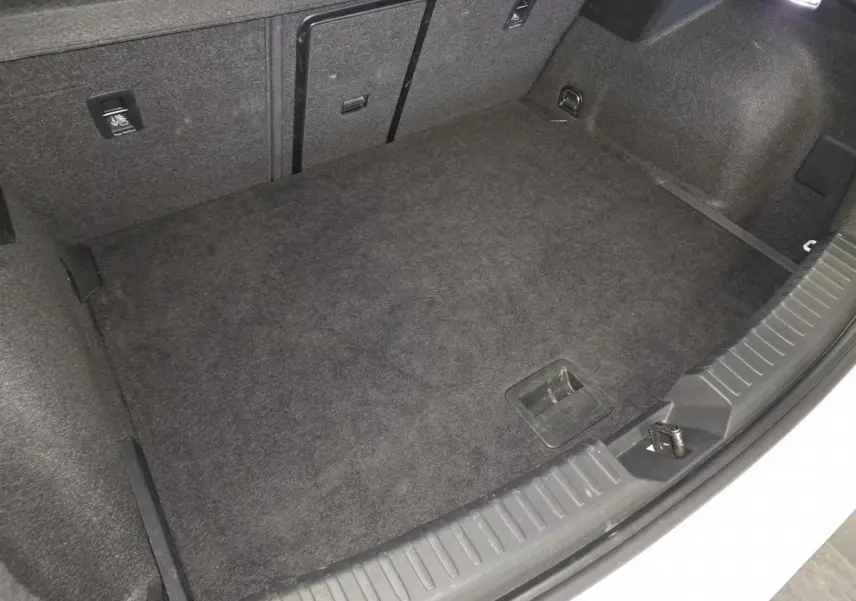 Coffre ouvert de la CUPRA Leon blanche, vue plongeante sur le tapis de coffre noir et les fixations internes.