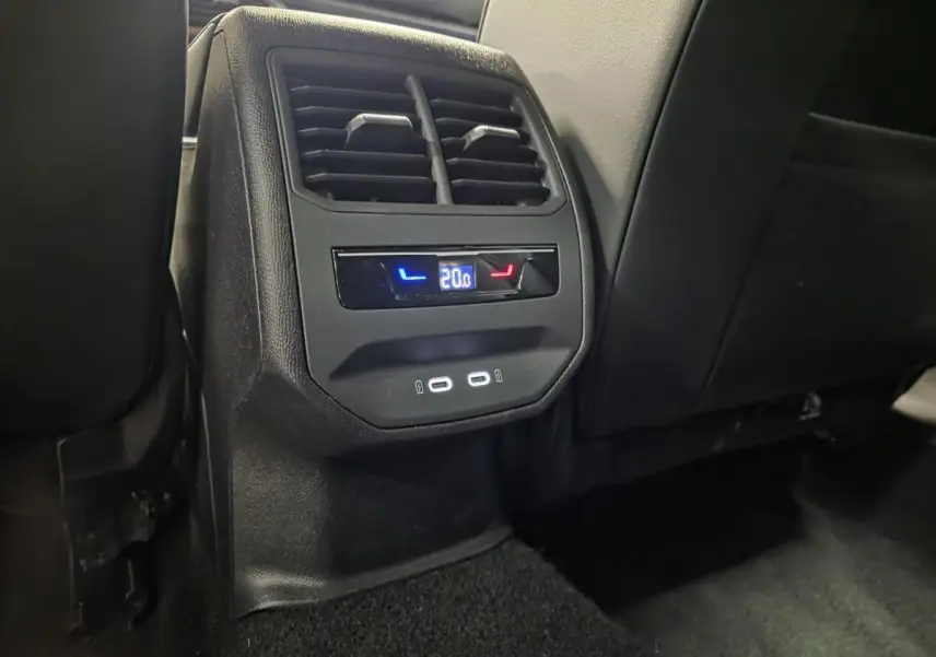 Vue rapprochée de la console arrière noire avec ventilation, réglage de climatisation à 20°C et deux prises USB-C éclairées.