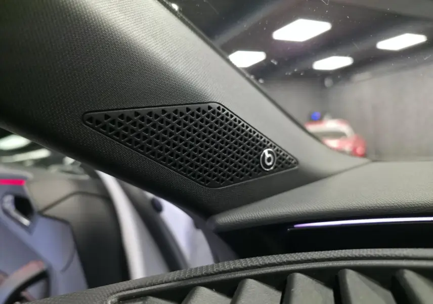 Gros plan sur le haut de la planche de bord côté gauche d’une CUPRA Leon blanche, avec haut-parleur Beats Audio intégré.